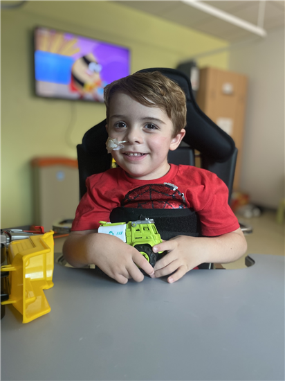 Freddie smiling while playing with toy trucks