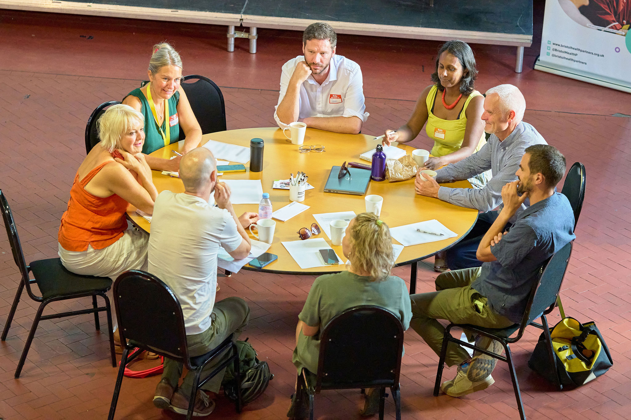 Eight members of our Council of Governors sat around a circular table talking to each other while several make notes with a pen and paper.