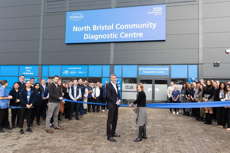 Geoff and Maria cut ribbon outside North Bristol Community Diagnostic Centre with crowd of healthcare colleagues gathered to celebrate