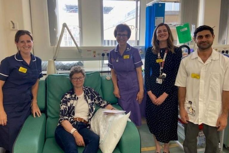 Four healthcare professionals and patient in treatment chair pose for group photo