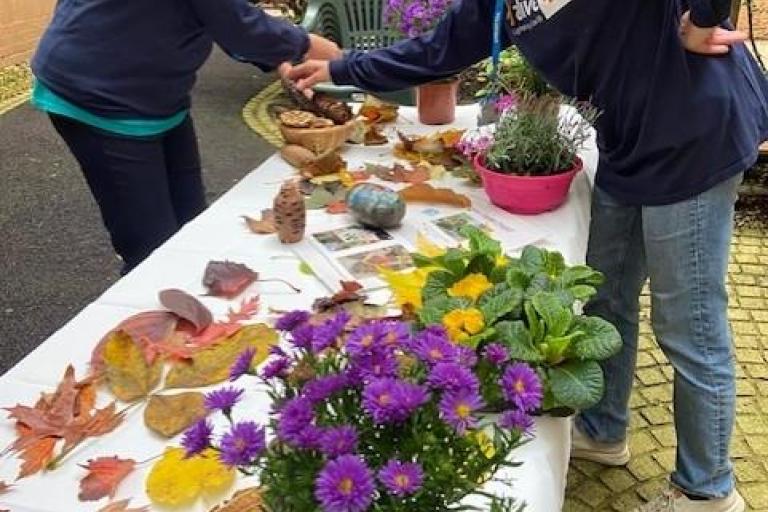 Two colleagues organising foliage on a table outside in a hospital garden