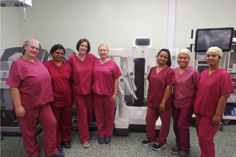 Group photo of UHBW surgical team next to surgical robot