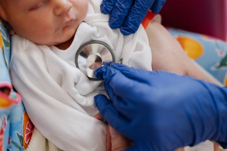 Newborn baby being examined with a stethoscope by a clinician
