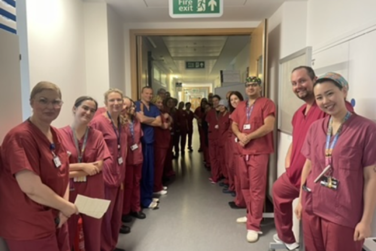 Neurosurgery theatre team pose for photo in clinical corridor