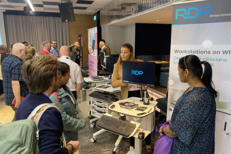 Attendees to the Health Tech Showcase event interacting at a supplier's stall.