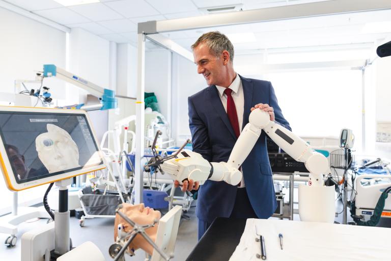 Rt Hon Peter Kyle MP, interacting with robotic surgical arm in clinical setting