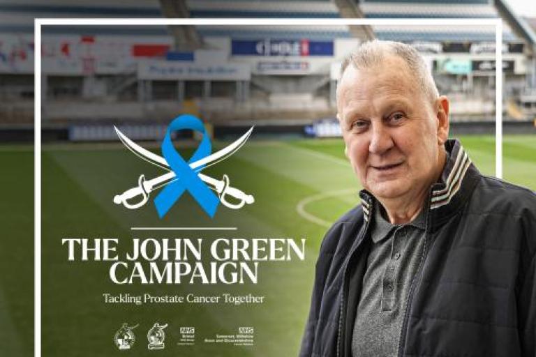 John Green smiling to camera with football pitch in background