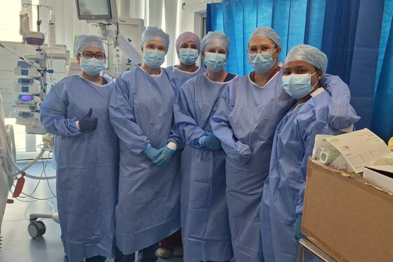 Colleagues from the Southmead Burns Unit and the BRI ICU dressed in scrubs and PPE grouped together on the ward.
