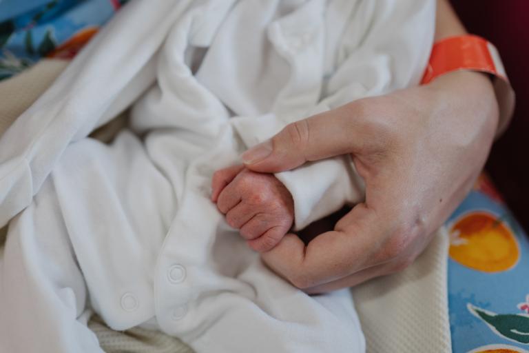 A parent holds a tiny newborn baby's hand at St Michael's Hospital, Bristol