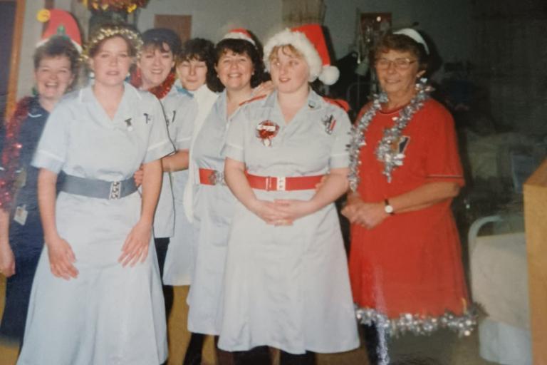 Nurses in uniform at Christmas party in 1990s with decorations hanging from the ceiling. 