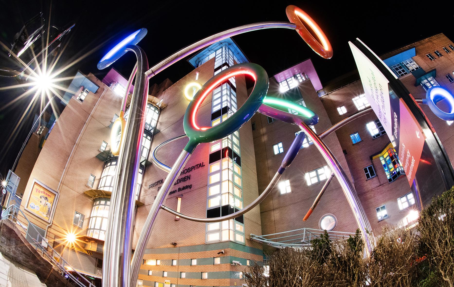 The front of Bristol Royal Hospital for Children at night, with the Hoops sculpture illuminated 