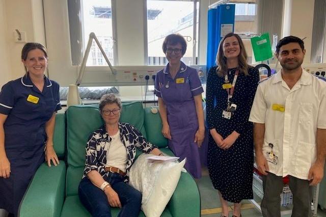 Four healthcare professionals and patient in treatment chair pose for group photo