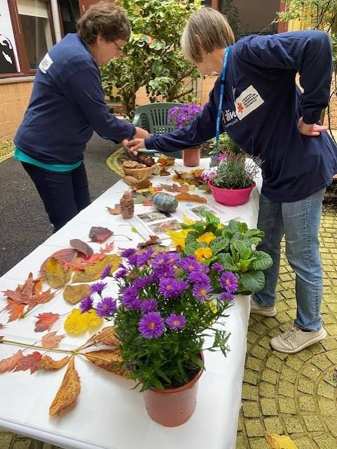 Two colleagues organising foliage on a table outside in a hospital garden