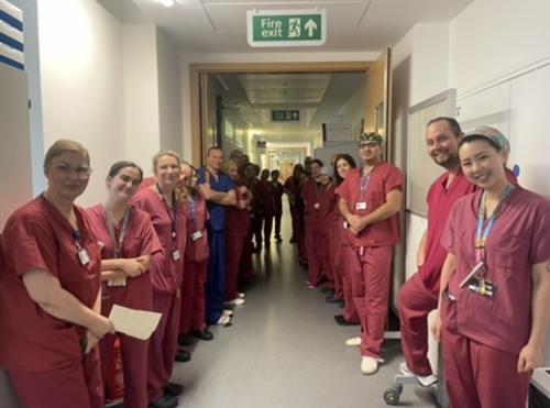 Neurosurgery theatre team pose for photo in clinical corridor