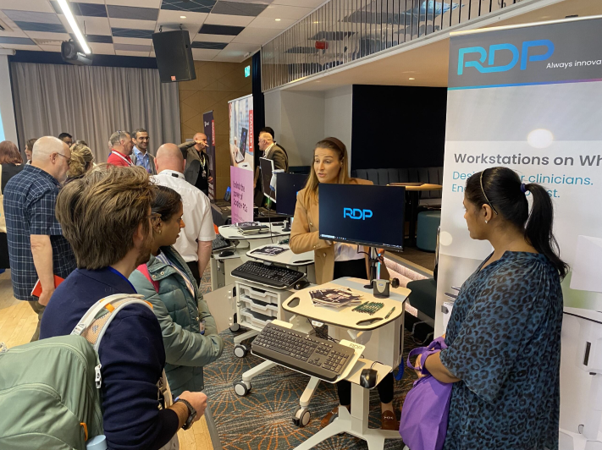 Attendees to the Health Tech Showcase event interacting at a supplier's stall.