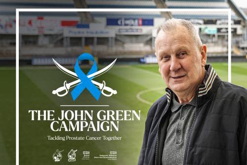 John Green smiling to camera with football pitch in background