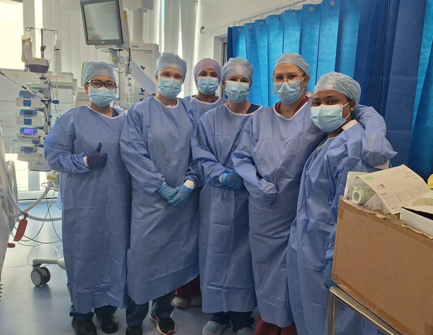 Colleagues from the Southmead Burns Unit and the BRI ICU dressed in scrubs and PPE grouped together on the ward.