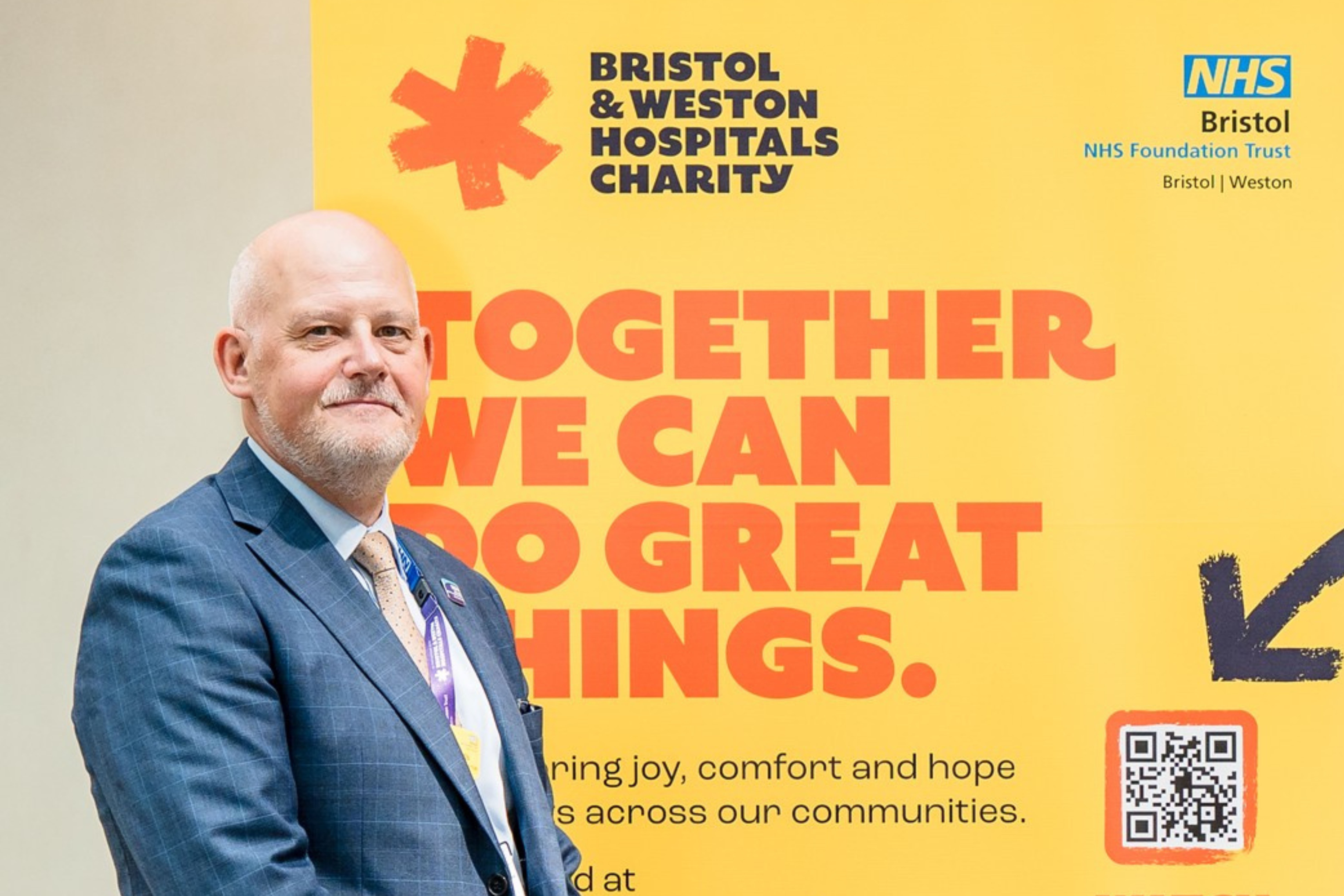 Glyn Howells standing beside a Bristol & Weston Hospitals Charity banner promoting a cycling fundraising challenge for Bristol NHS Foundation Trust Landscape