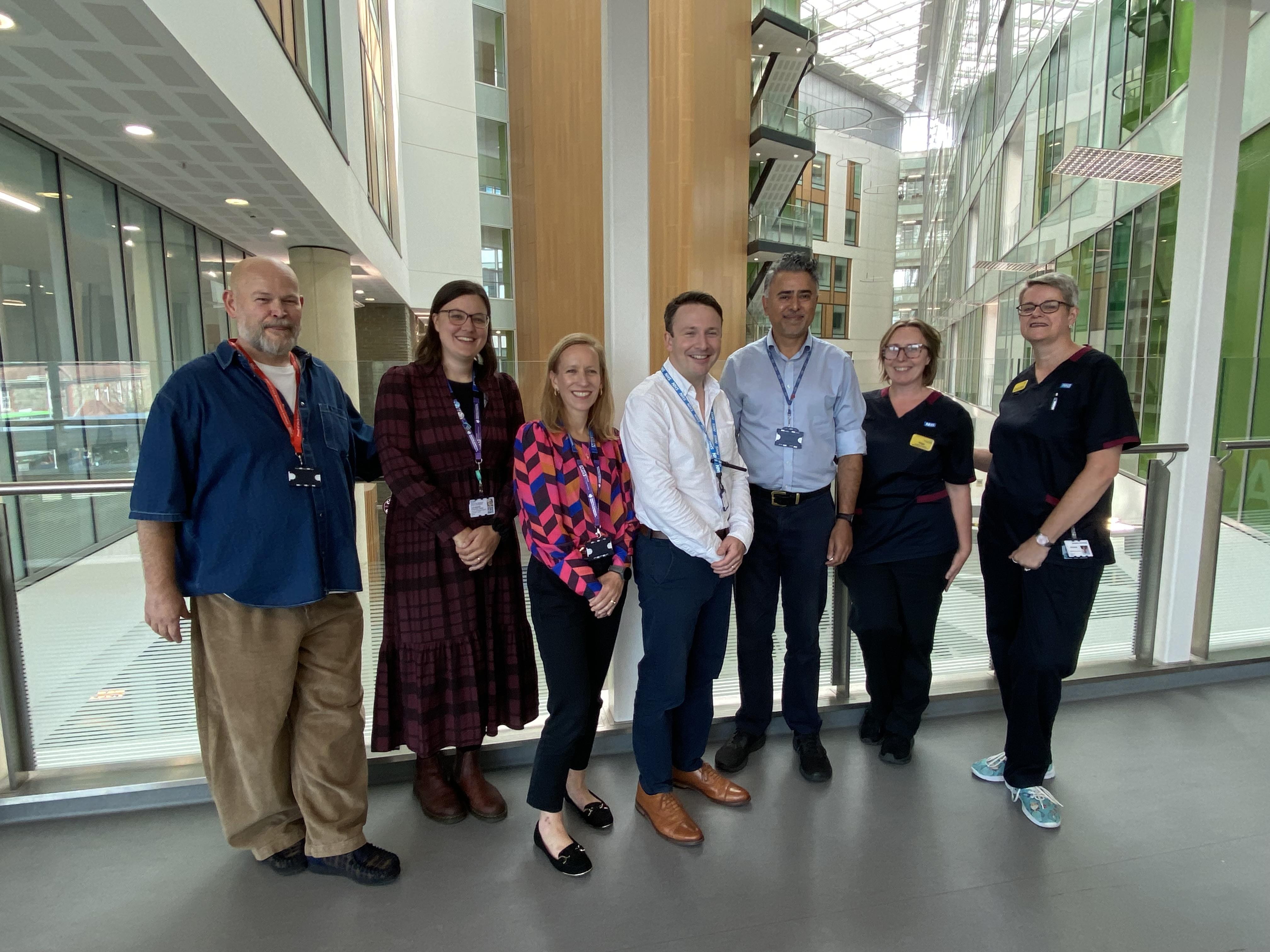 The cardiology and digital services project team are grouped together smiling in the Brunel Atrium at Southmead Hospital.